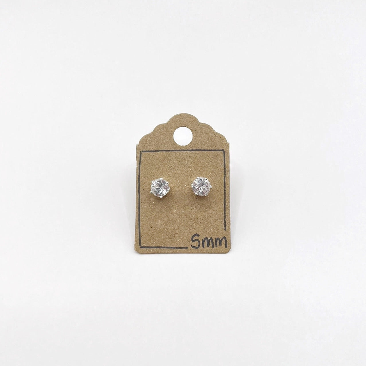 Pair of silver stud earrings with clear cut glass on a small cardboard backing with '5mm' text.