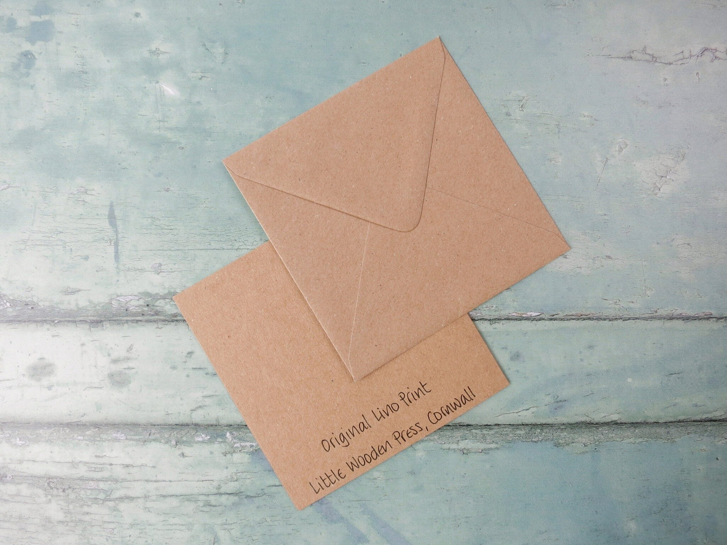 Showing the back of the card with text and matching Kraft envelope laid on a textured background