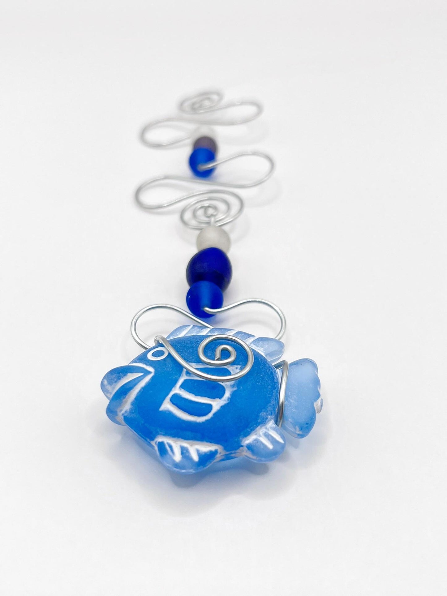 Decorative hanging ornament with blue fish design, wire and glass beads on a white background