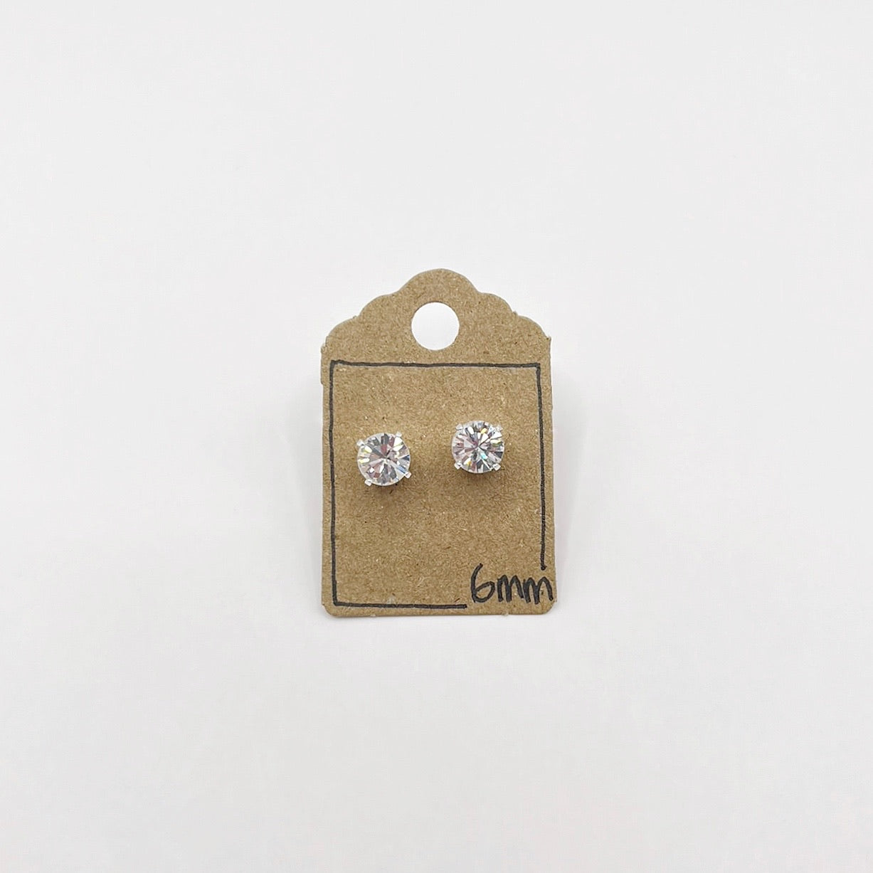 Pair of silver stud earrings with clear cut glass on a cardboard backing with '6mm' text.