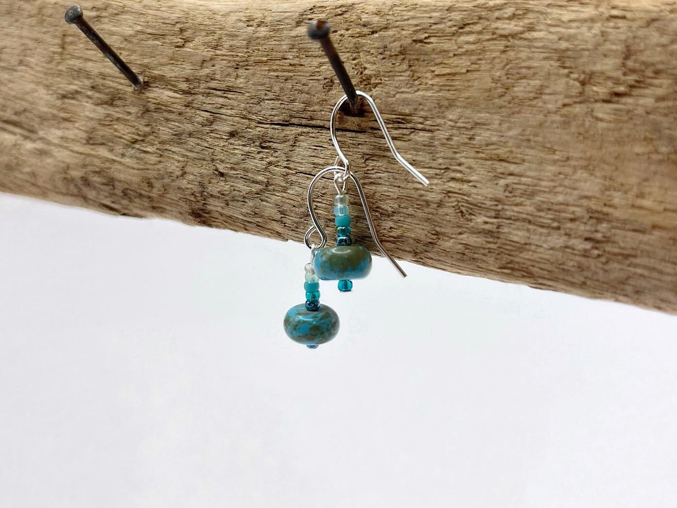 Turquoise beaded earrings hanging on driftwood