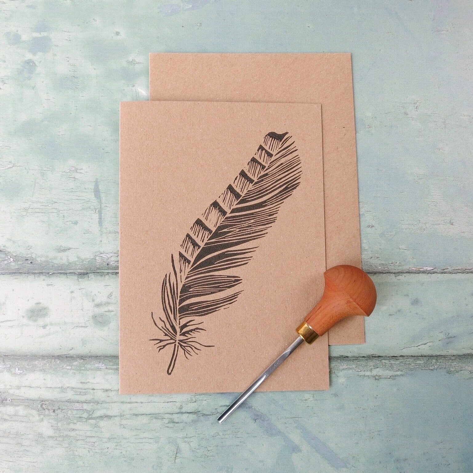 Kraft paper card with feather design. Photo includes lino cutting tool used 