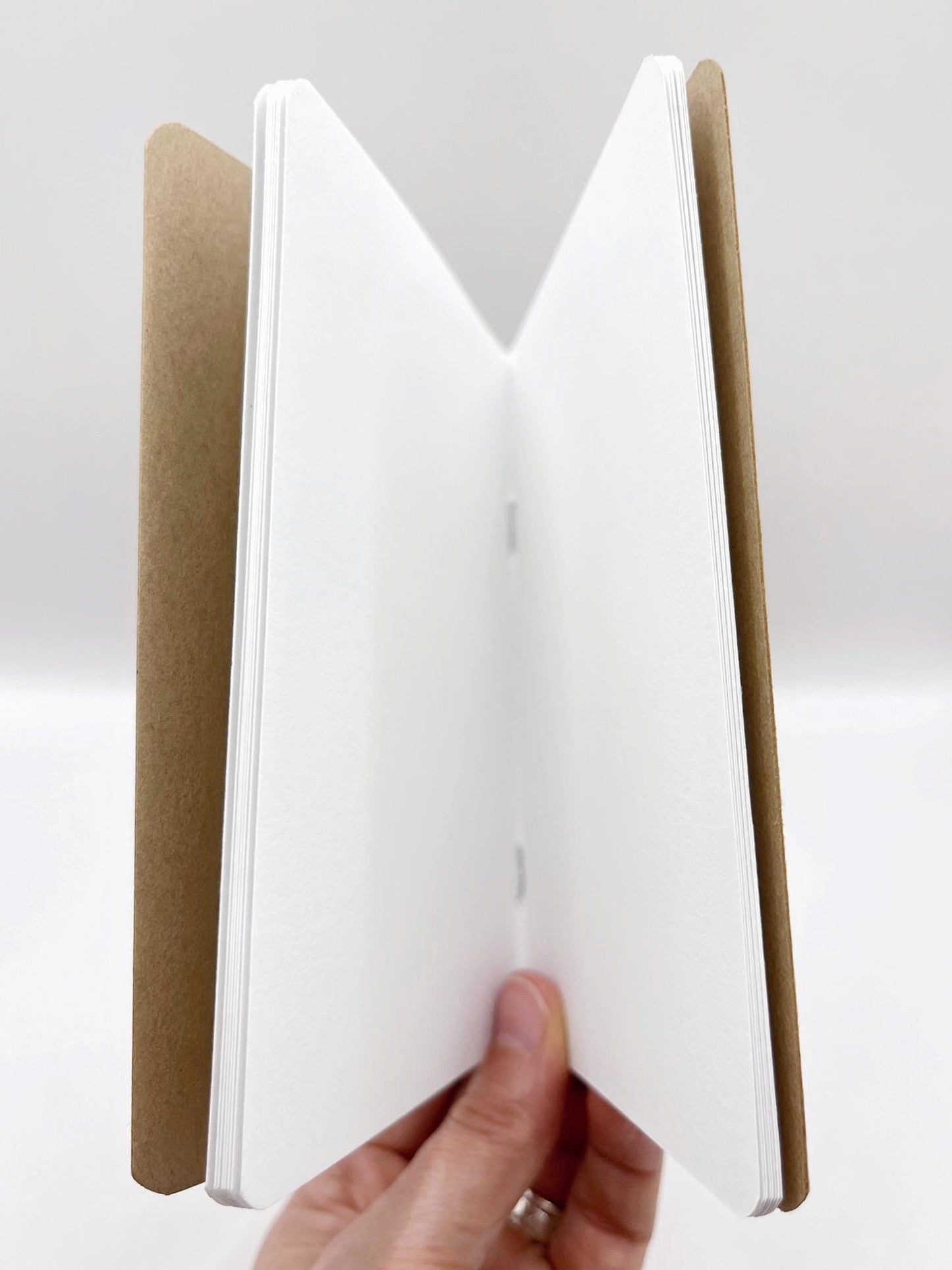 Open notebook with a brown cover held by a hand on a white background