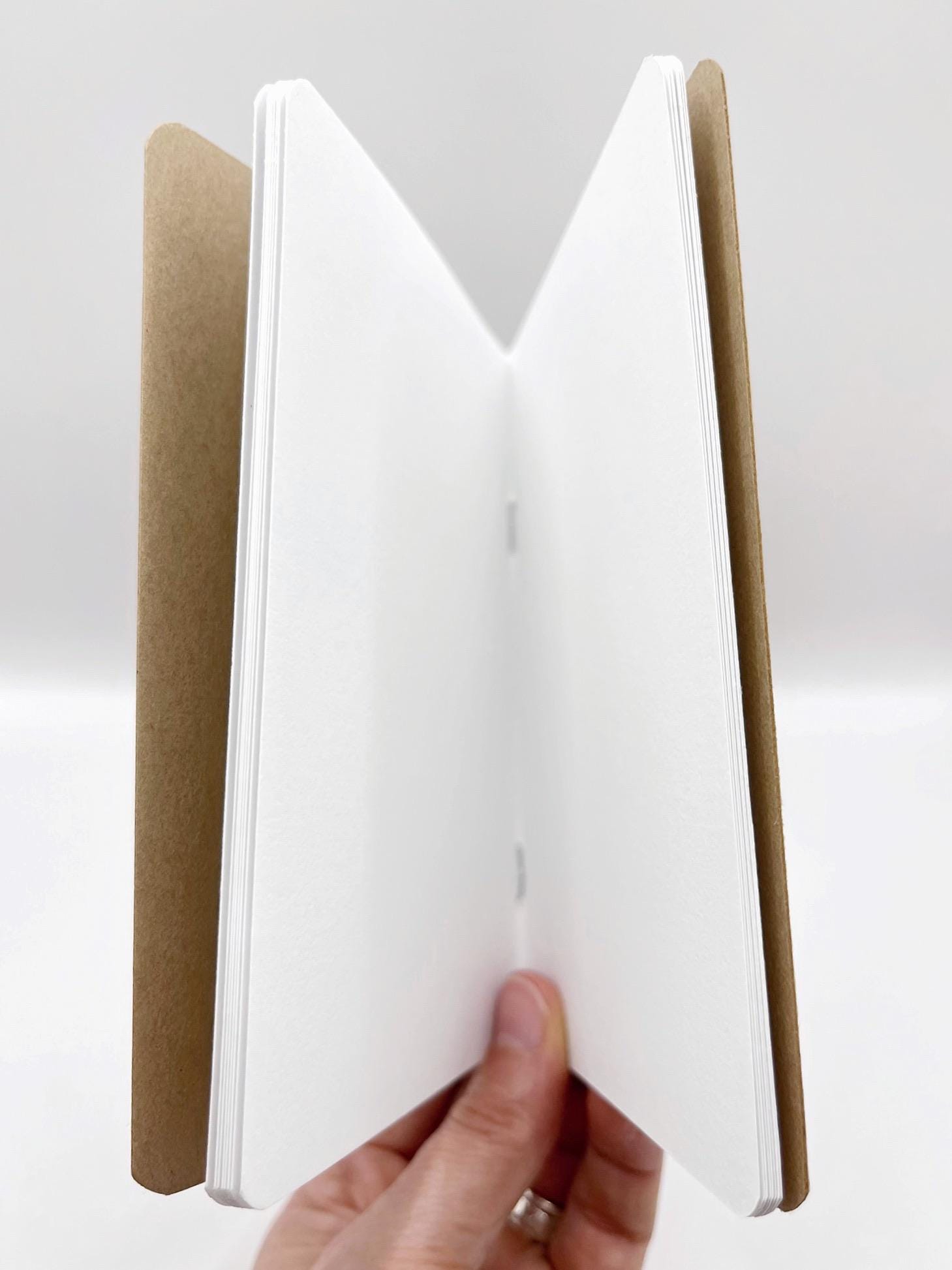 Open notebook with a brown cover held by a hand on a white background