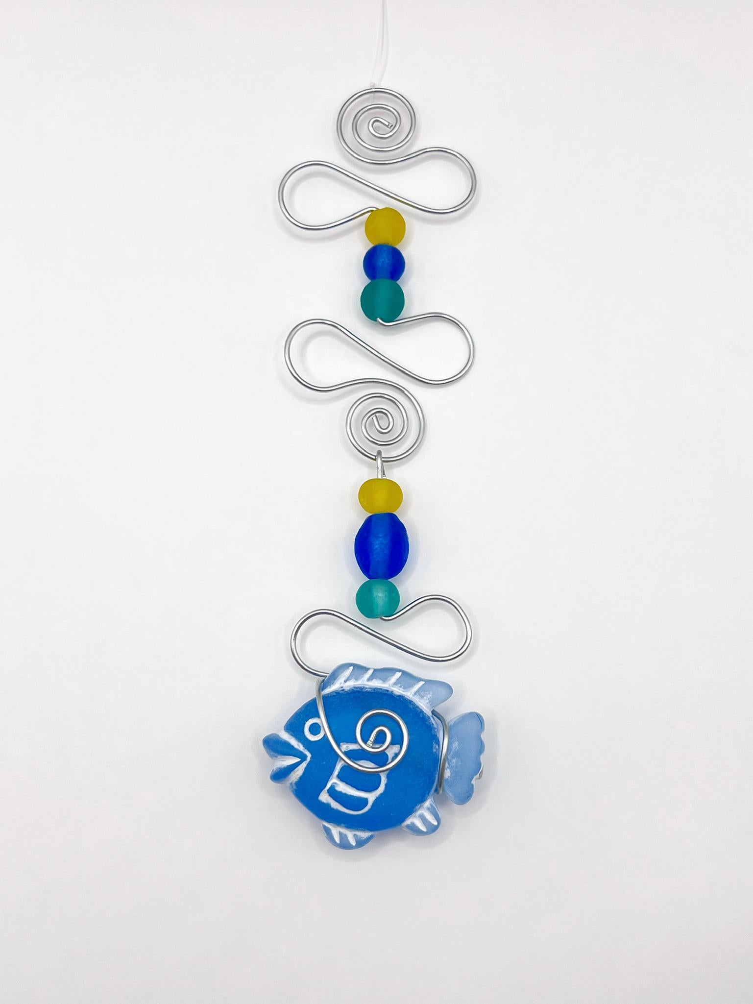 Decorative ornament with blue fish design, wire and colourful beads on a white background