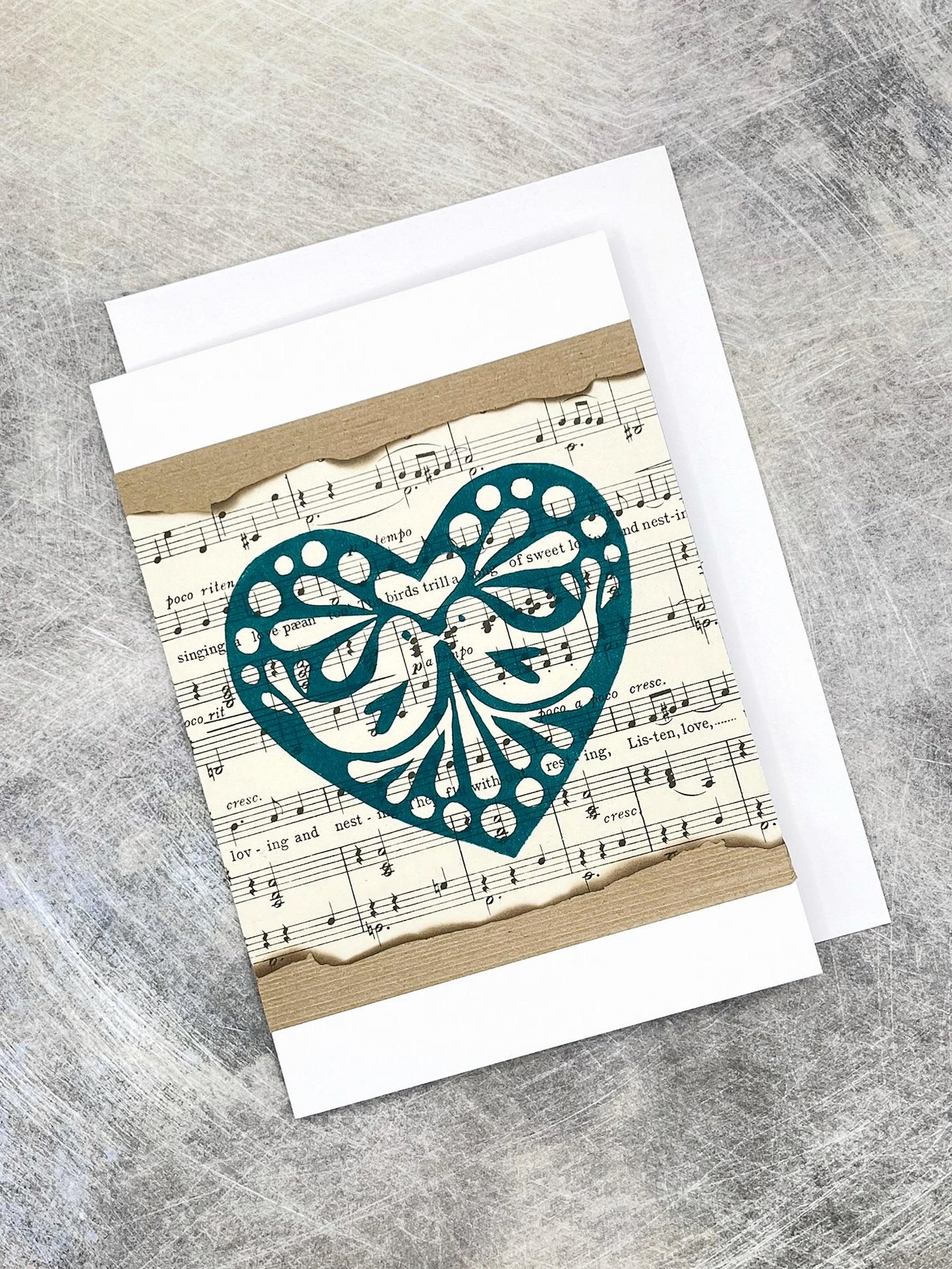 Greeting card with decorative heart design on sheet music, laid on a grey surface 
