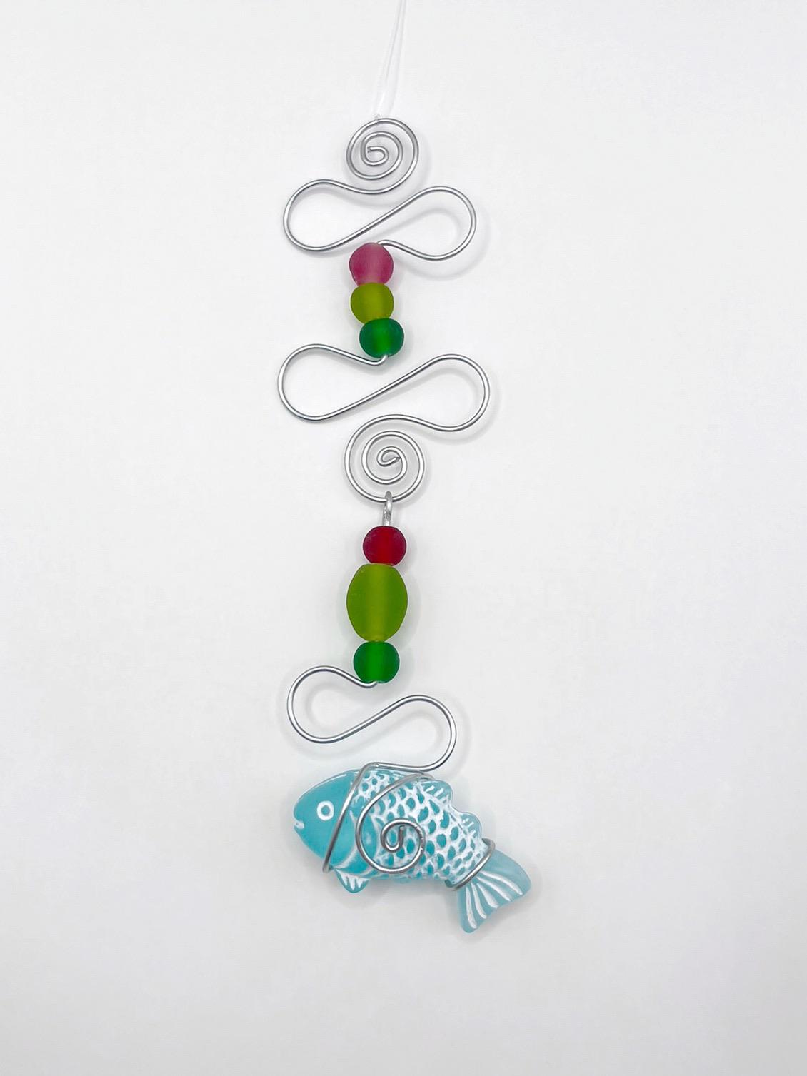 Decorative hanging ornament with a fish design, wire and colourful beads on a white background
