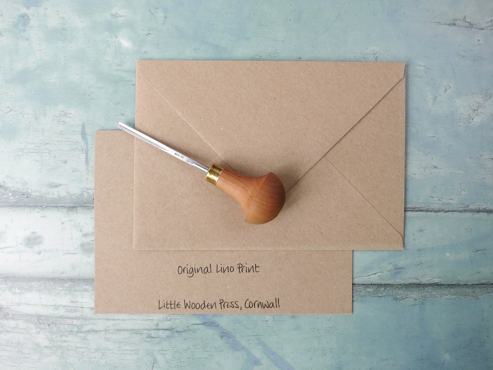 Showing the back of the card with text and matching Kraft envelope. Photo includes lino cutting tool