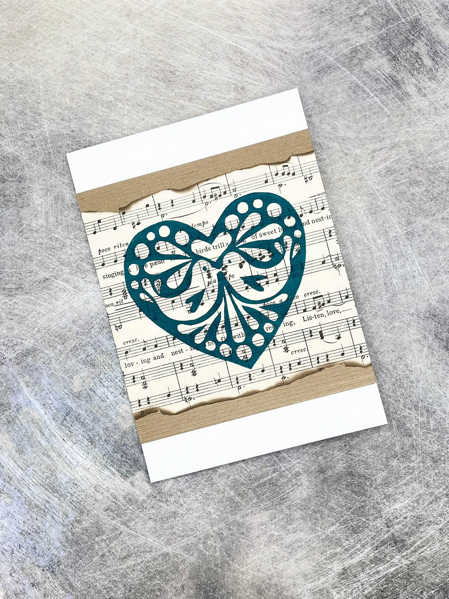 Card with green heart design on sheet music laid on a textured background.