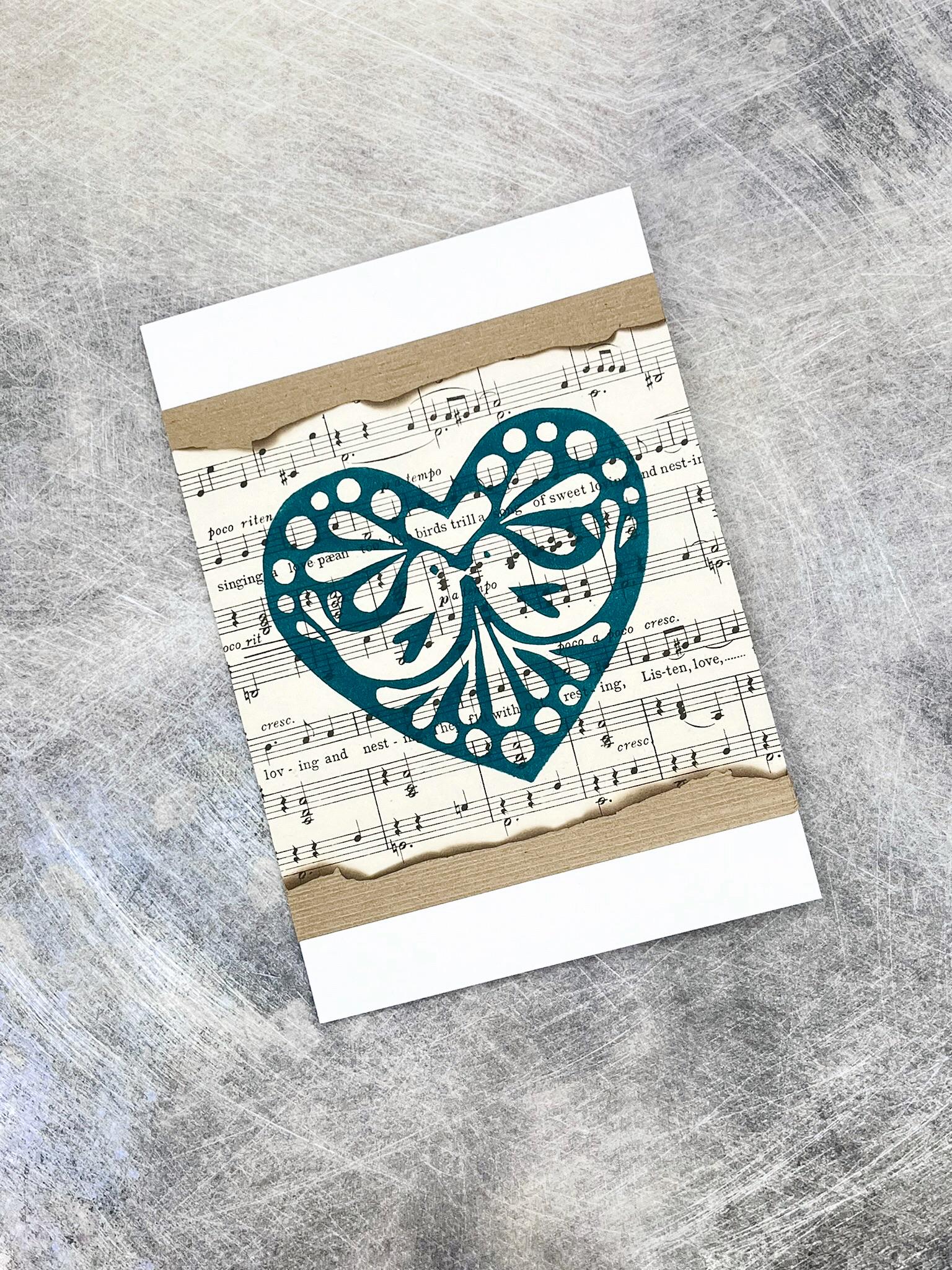 Card with green heart design on sheet music laid on a textured background.