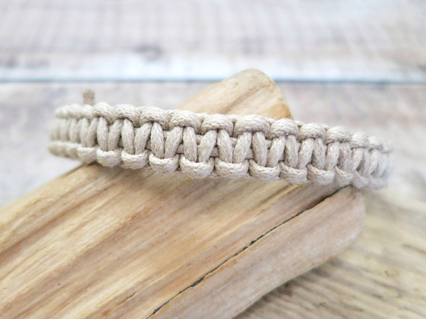 Natural coloured macrame bracelet on a wooden surface with a blurred background