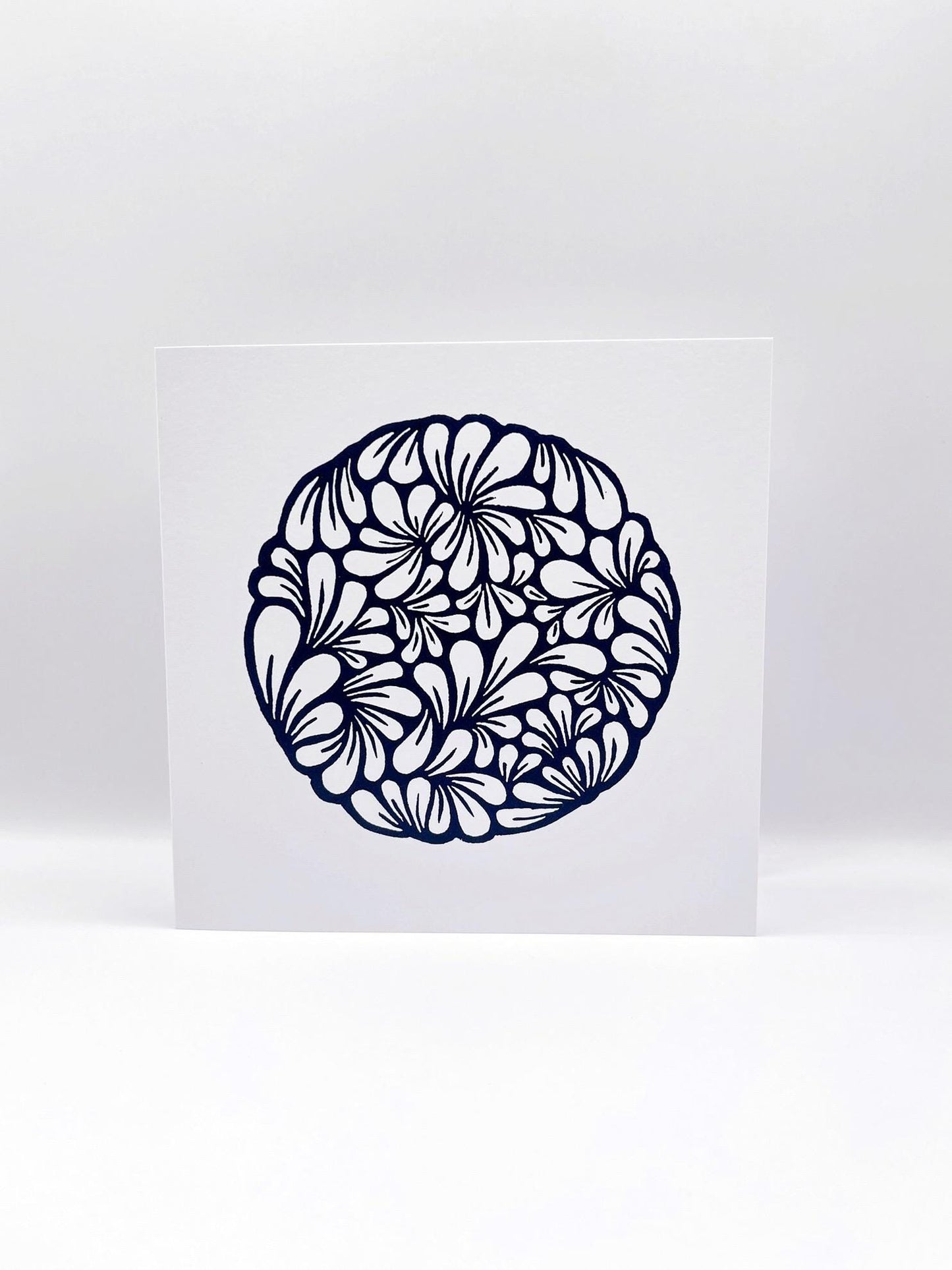 Original navy blue lino printed mussel shell pattern on white card stood against a white background