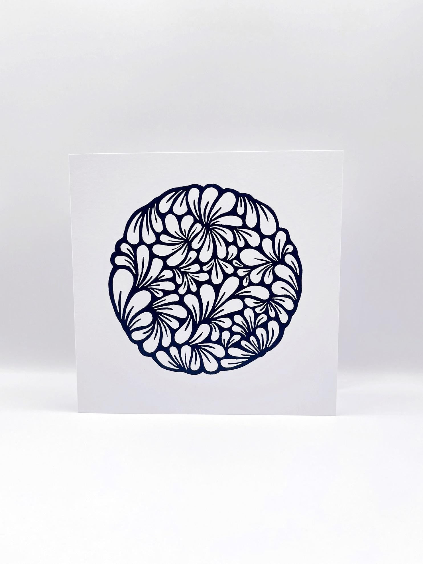 Original navy blue lino printed mussel shell pattern on white card stood against a white background