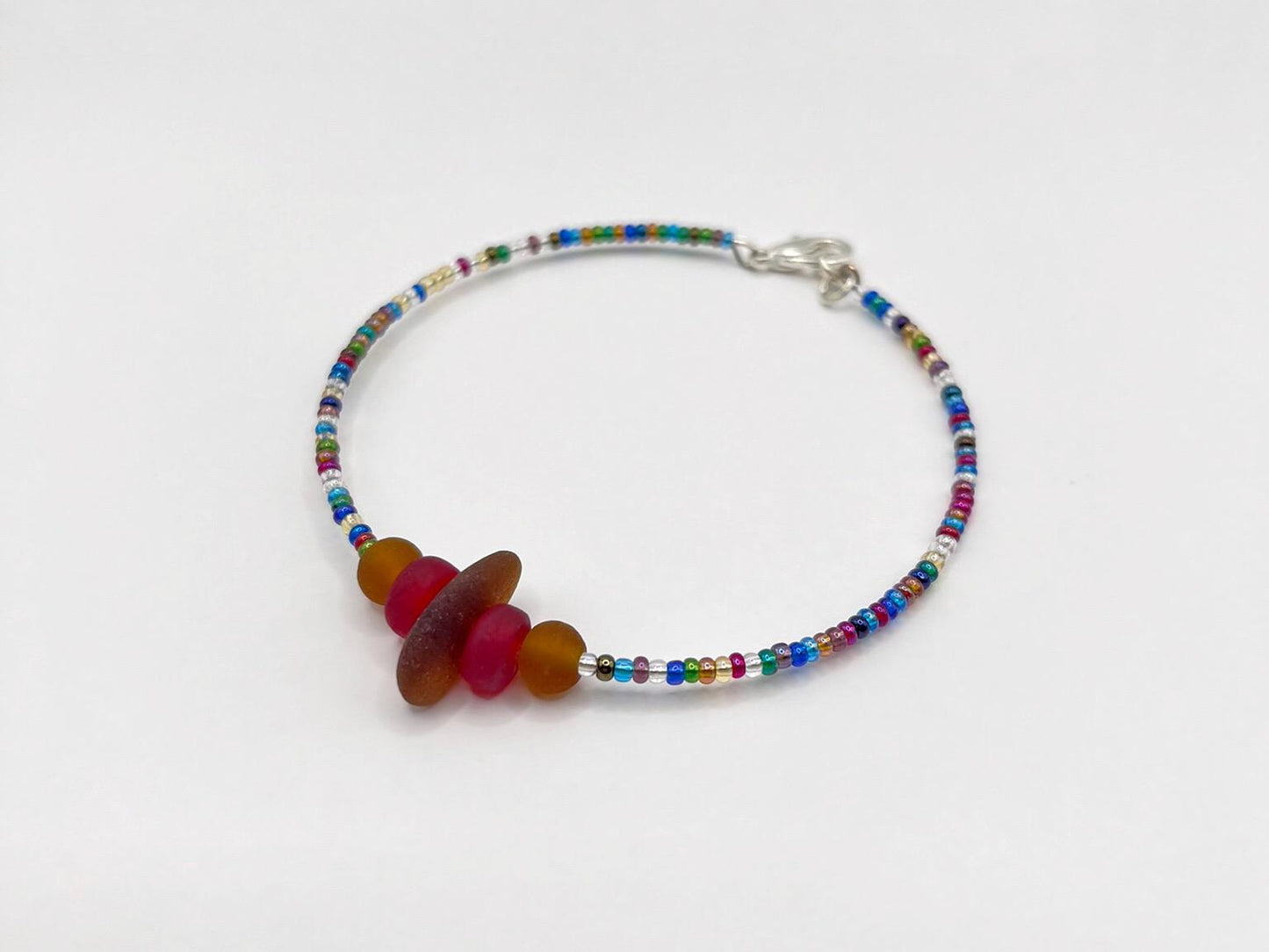 Rainbow beaded bracelet with sea glass and frosted glass beads laid on a white background