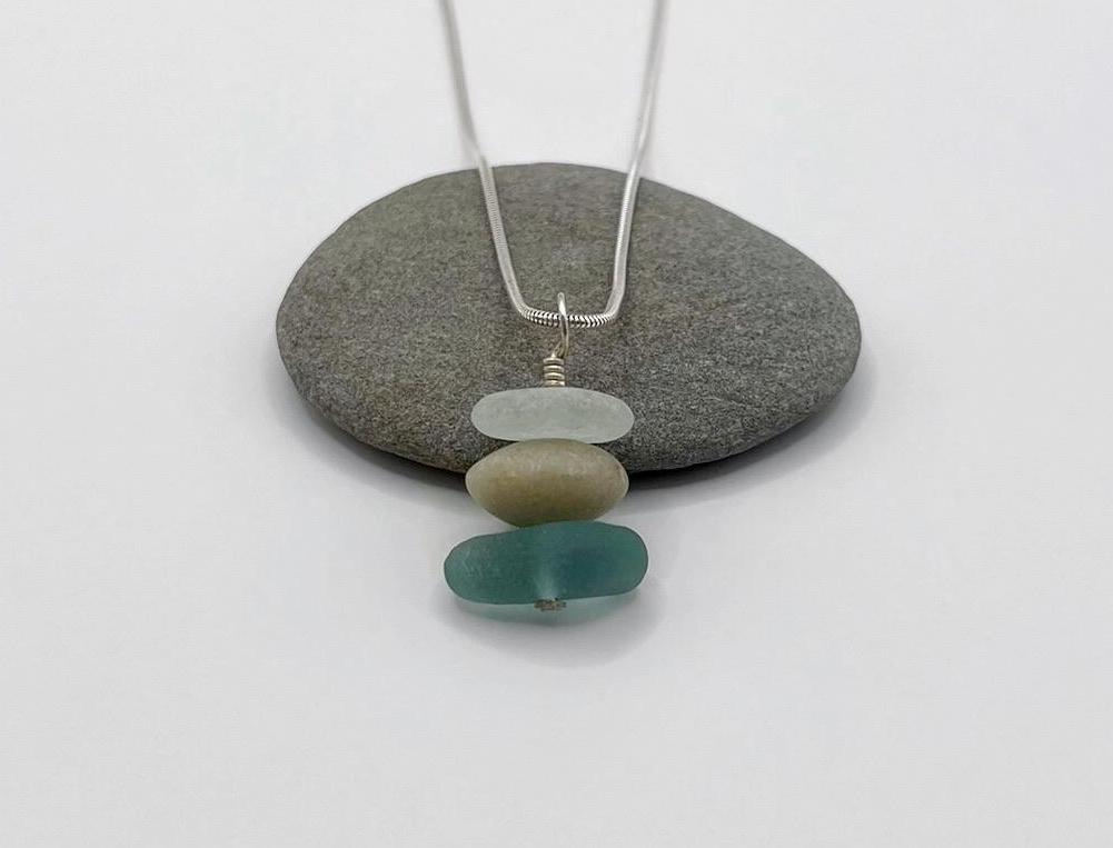 Necklace with sea glass and a Jade bead laid on a grey stone against a white background