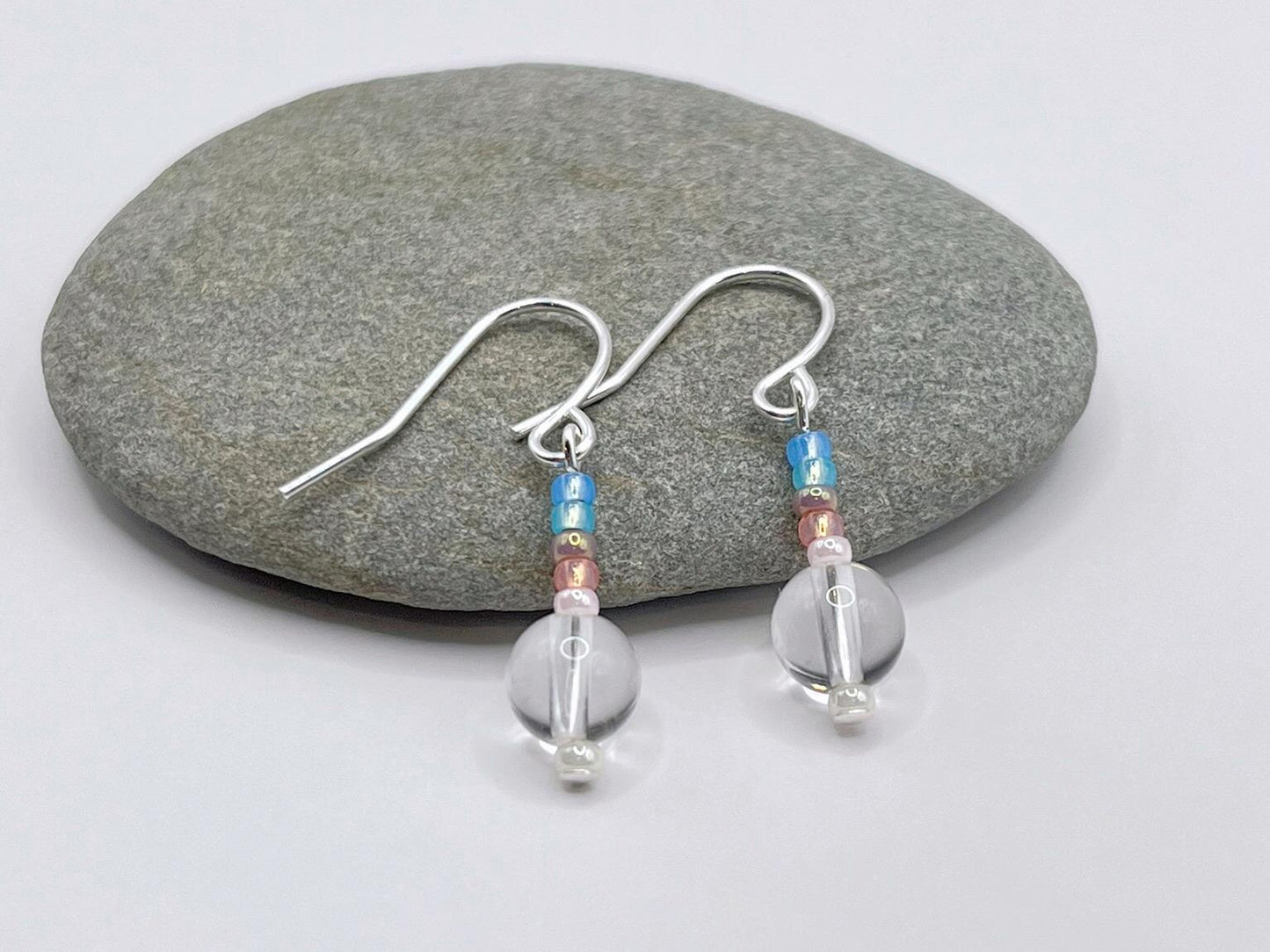 Pair of earrings with crystal and pastel seed beads laid on a grey pebble