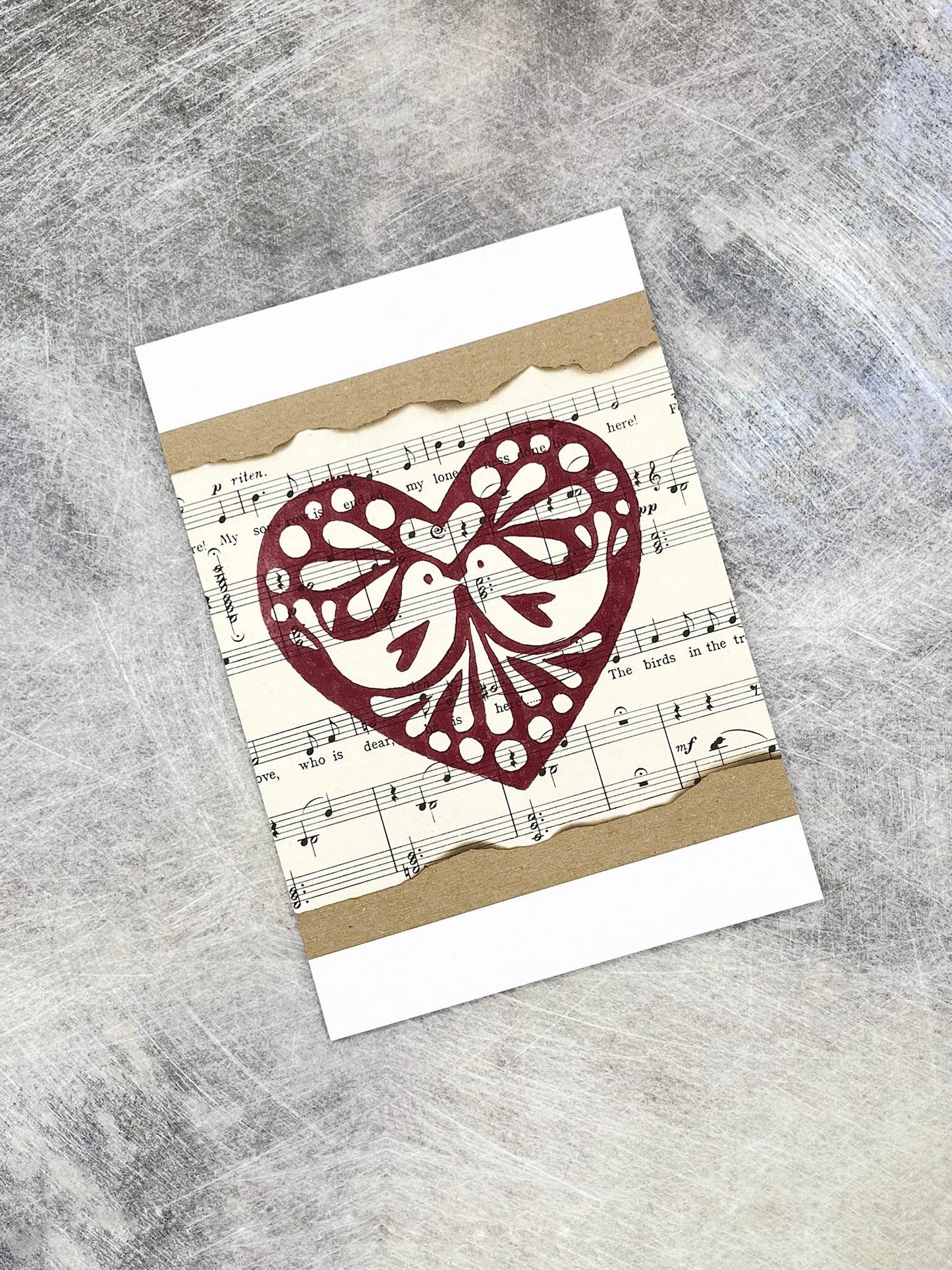 Card with original lino printed heart design on sheet music laid on a textured background