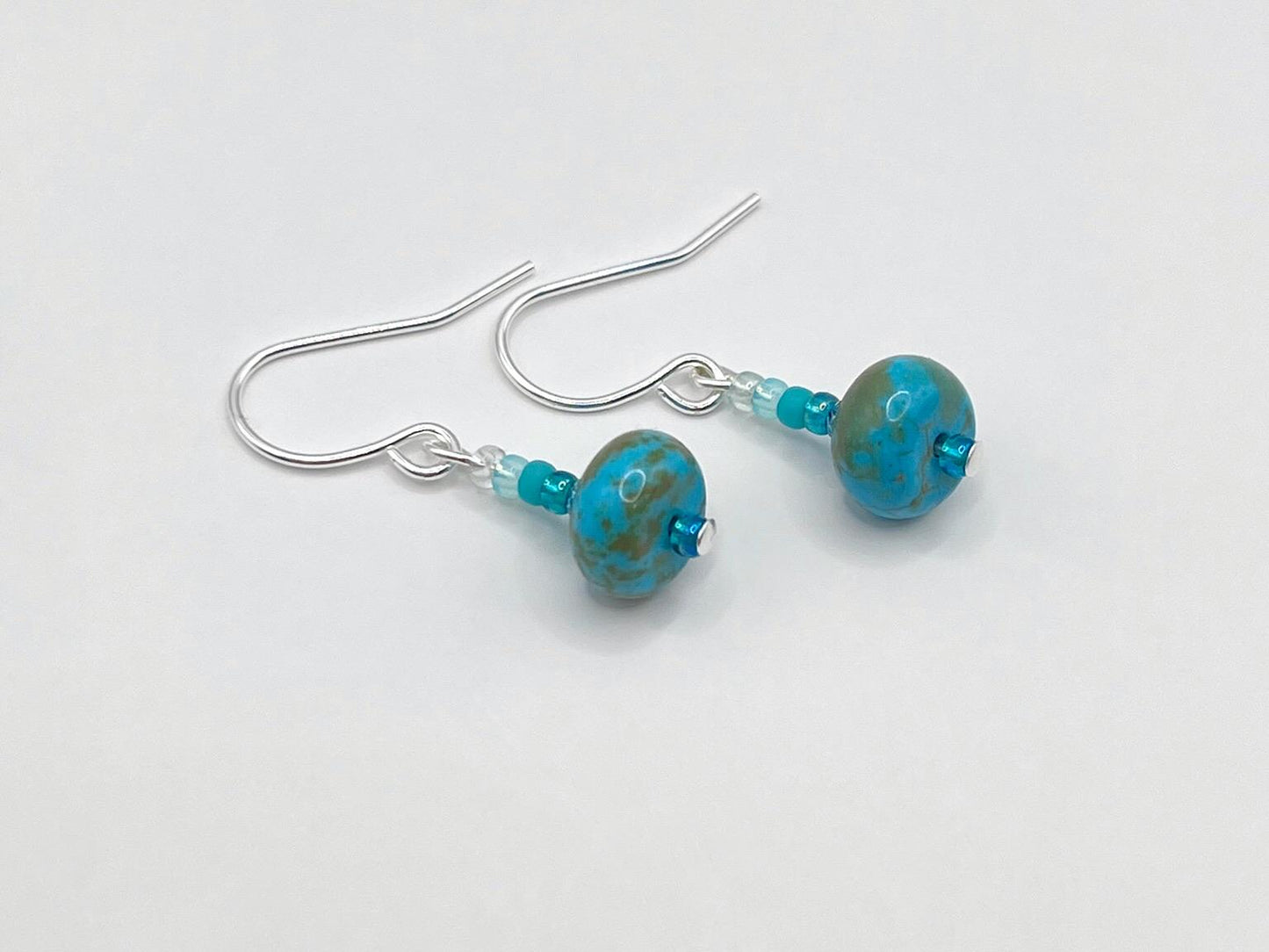 Pair of turquoise glass bead earrings on a white background