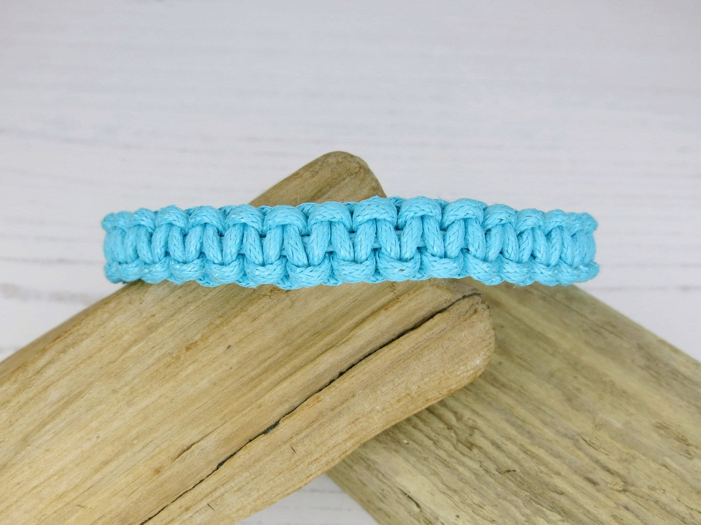 Turquoise macrame bracelet on a wooden surface with a light gray background