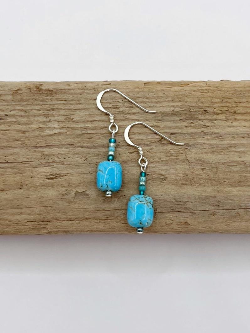 Turquoise beaded earrings on a wooden surface