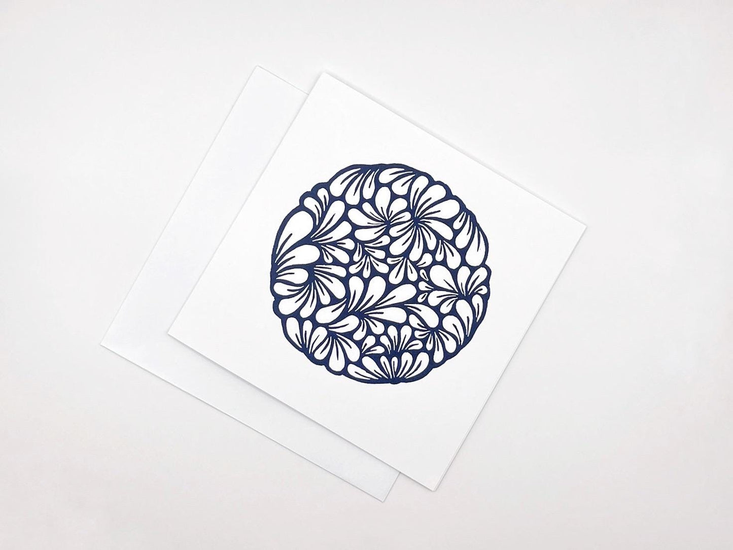 Original navy blue lino printed mussel shell pattern on white card laid on a white background.