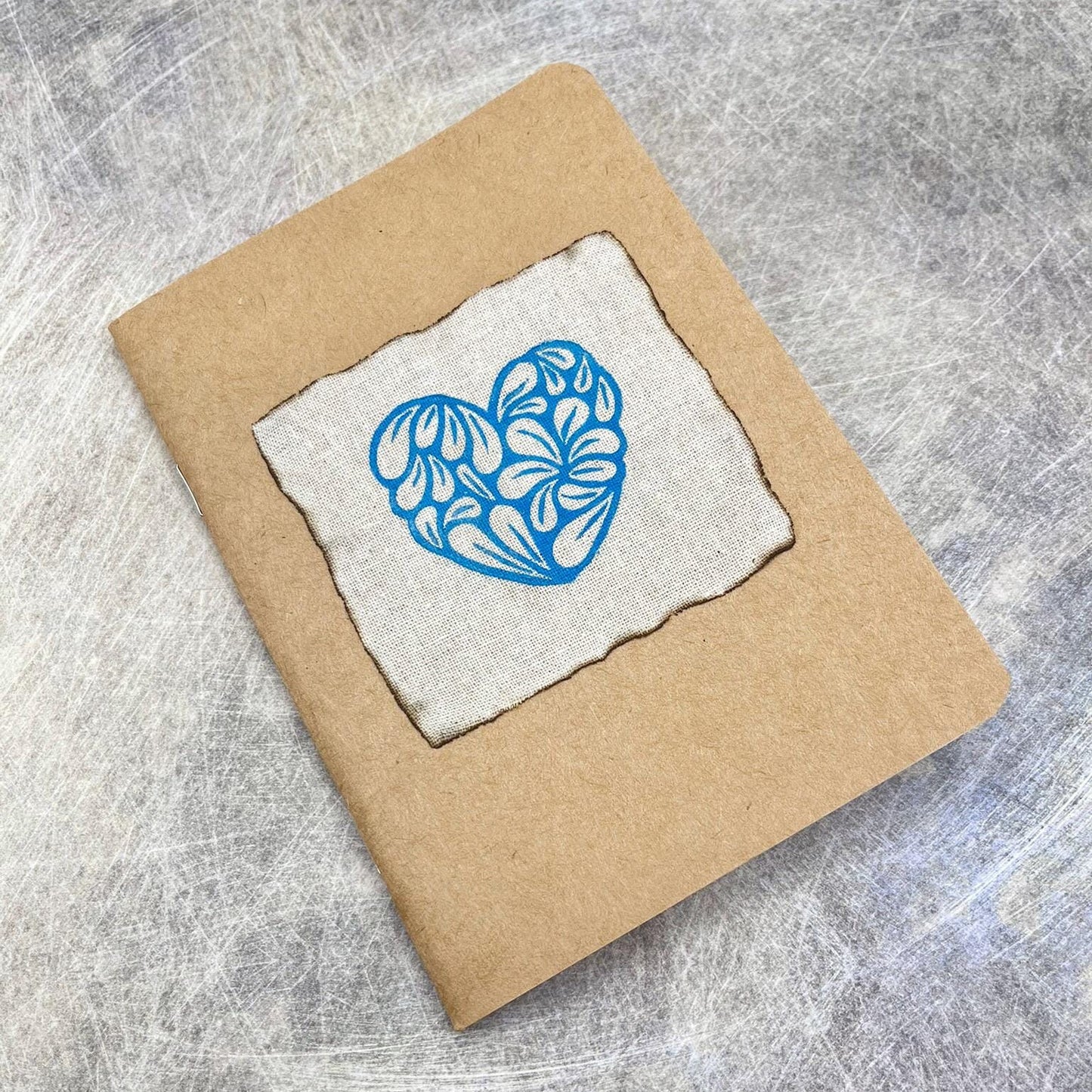 A6 Kraft sketchbook with blue floral heart design on a textured grey background