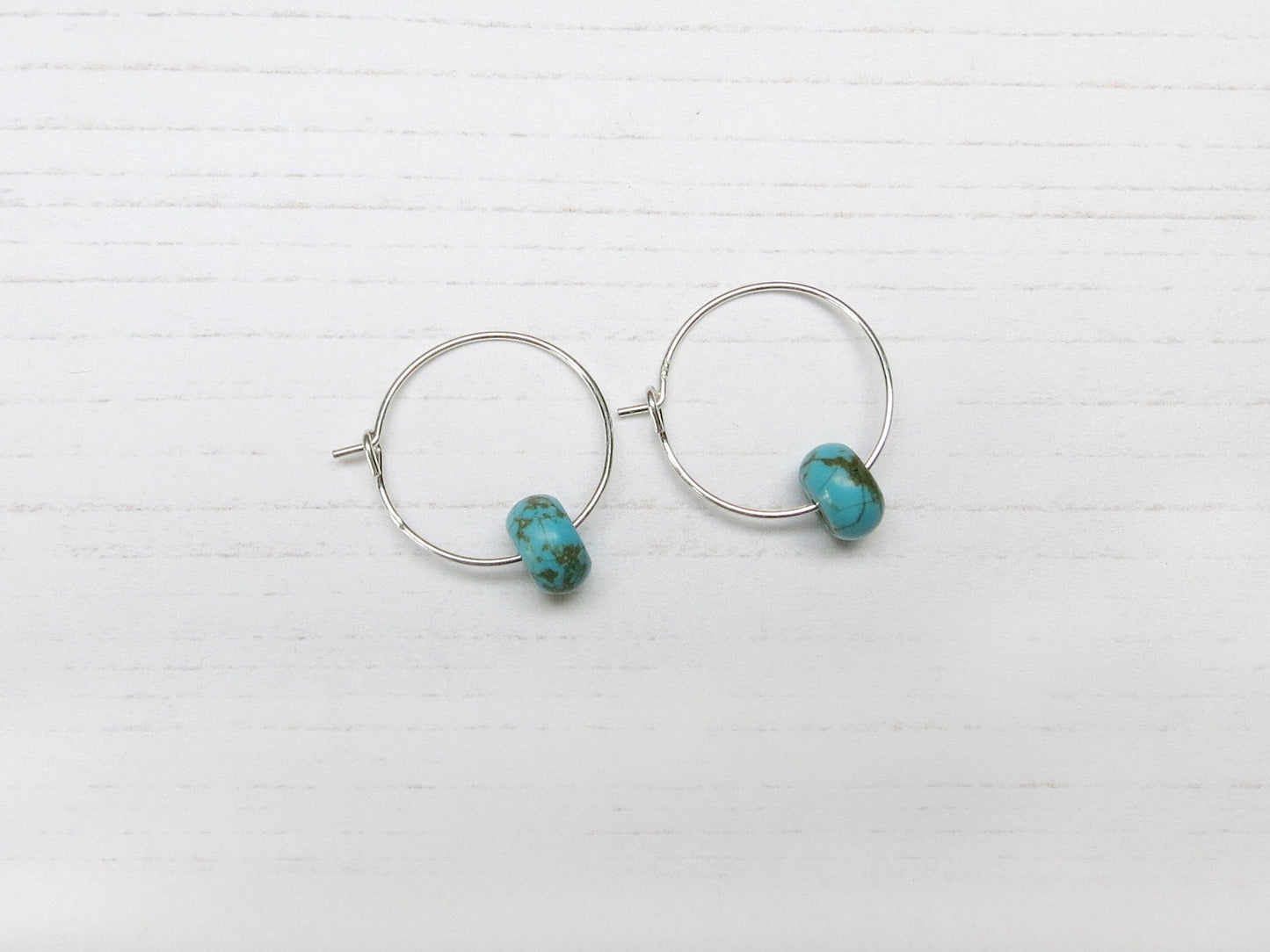 Silver hoop earrings with turquoise beads on a white background