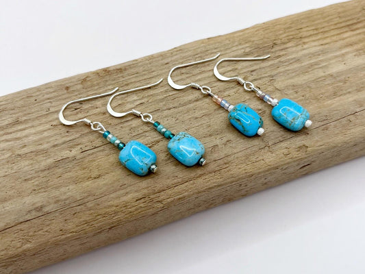 Turquoise beaded earrings on a wooden surface