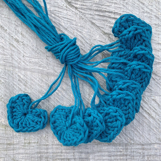 Ten teal crochet hearts laid on a textured background