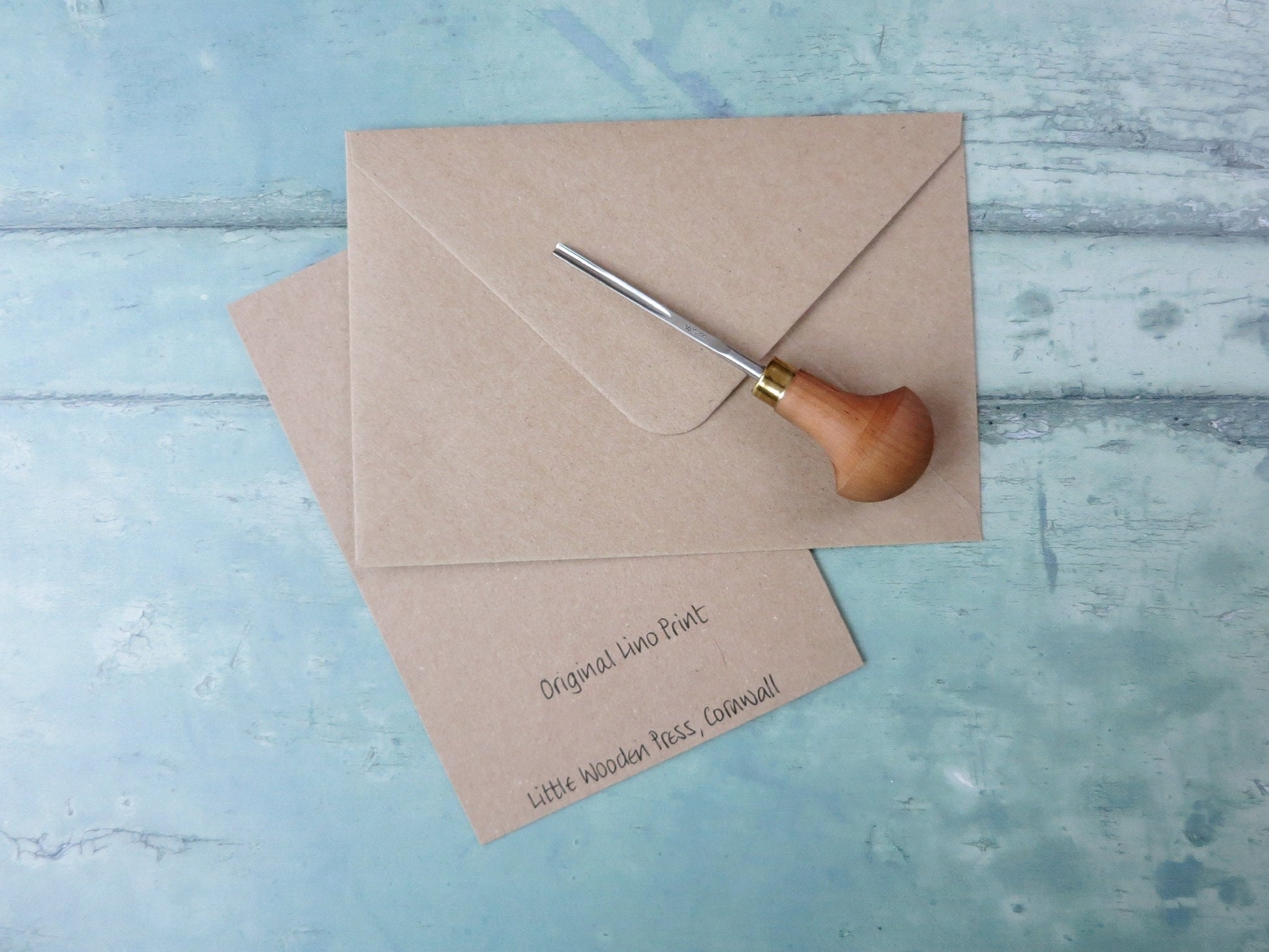 Showing the back of the card with text and matching Kraft envelope. Photo includes lino cutting tool