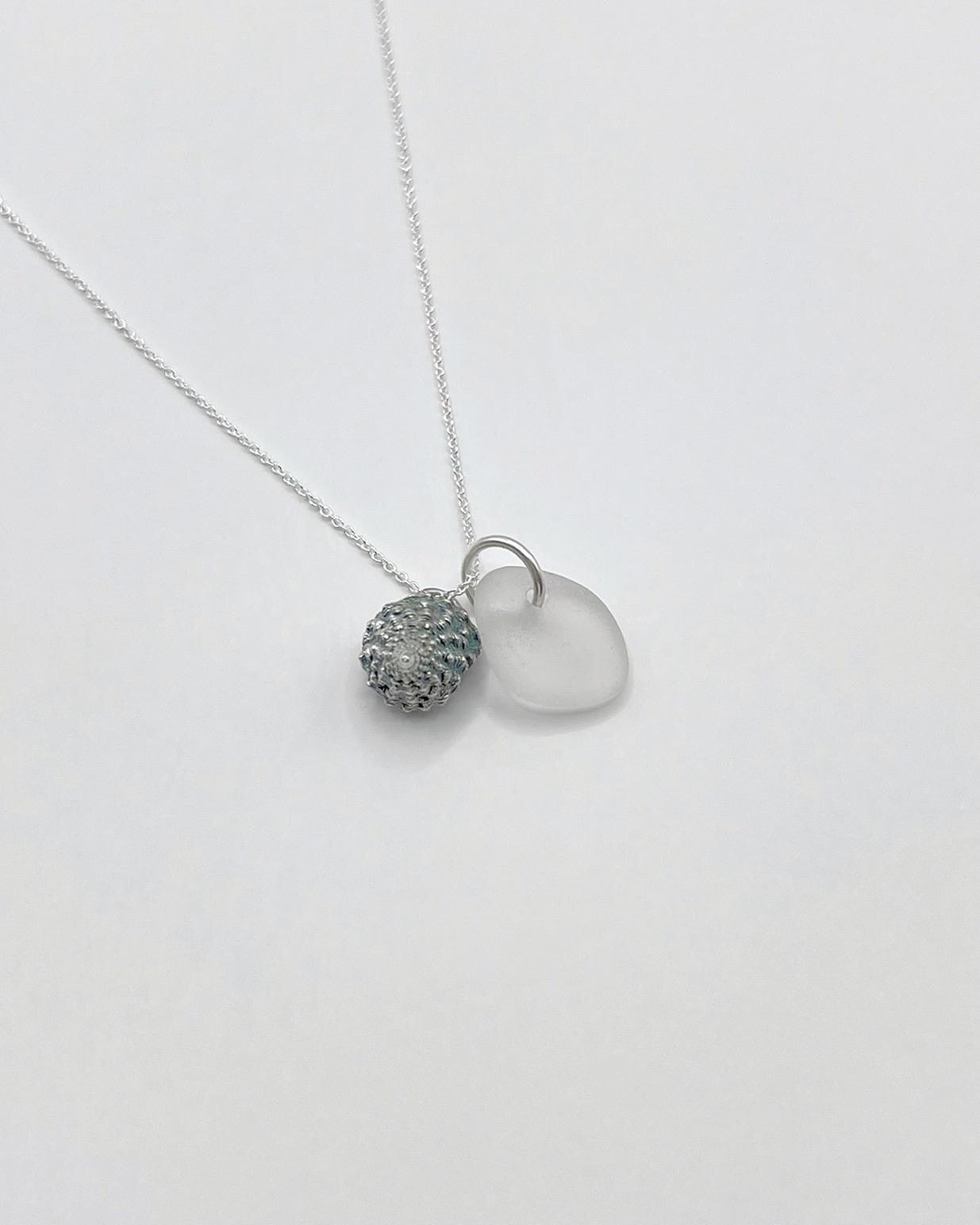 Silver necklace with White Sea glass and silver shell pendant laid on a white background