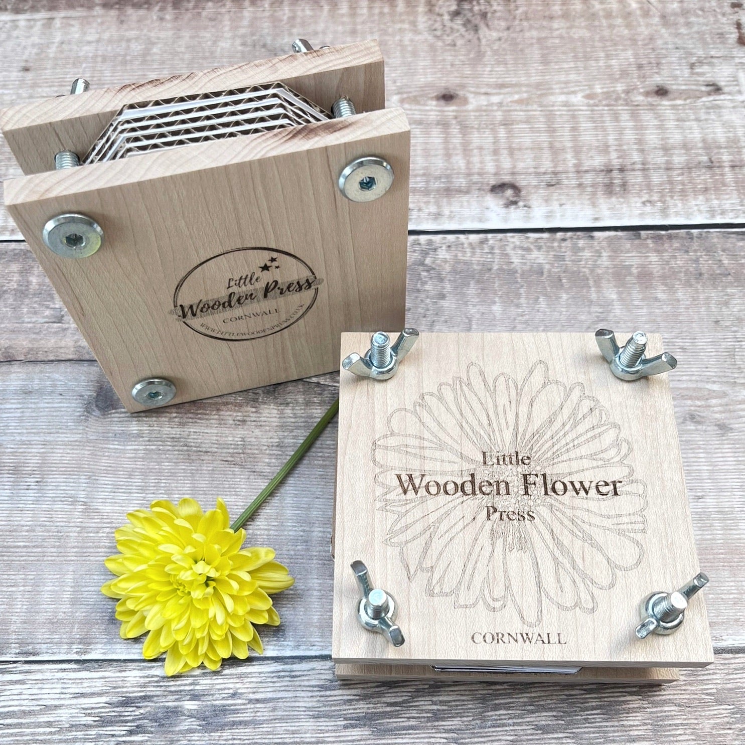 Little Wooden Flower Press with a yellow flower stood on a wooden surface