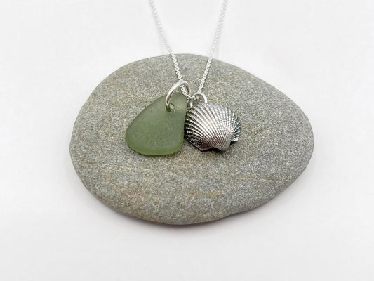 Necklace with green sea glass and silver shell pendant laid on a grey pebble
