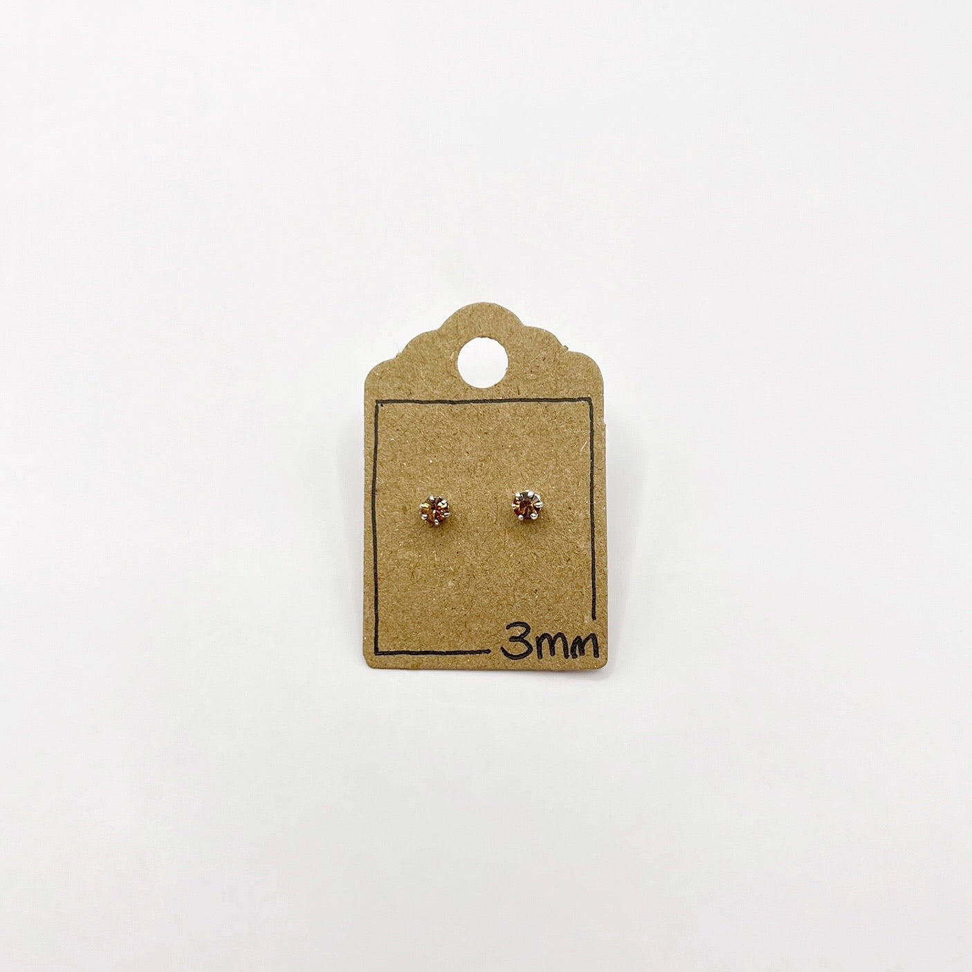 Pair of small cut glass stud earrings on a brown cardboard card with '3mm' marking on a white background