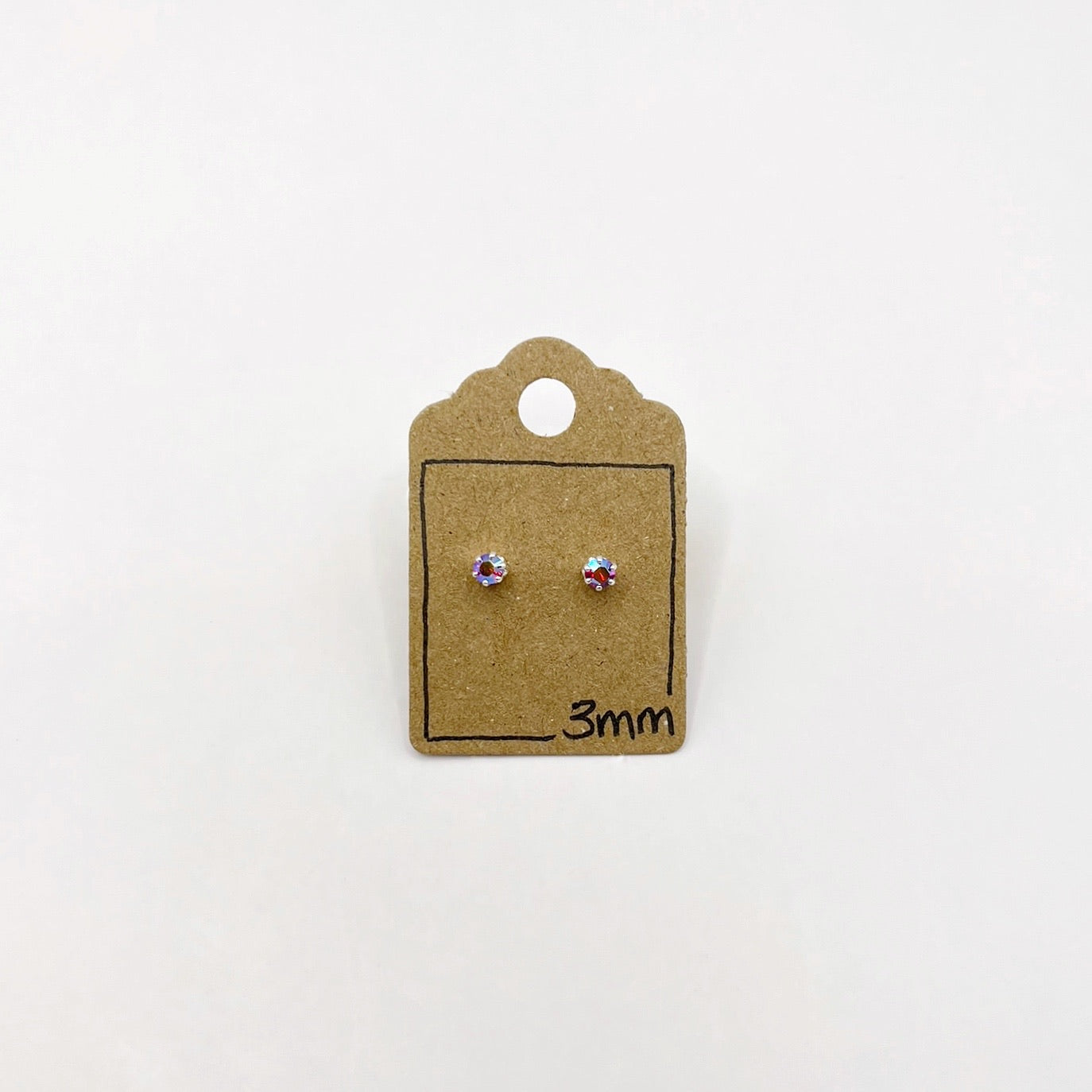 Pair of sparkly glass stud earrings on a small cardboard stand with '3mm' marking on a white background
