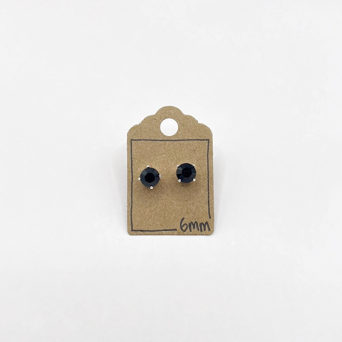 Black stud earrings on a small cardboard stand with '6mm' marking on a white background
