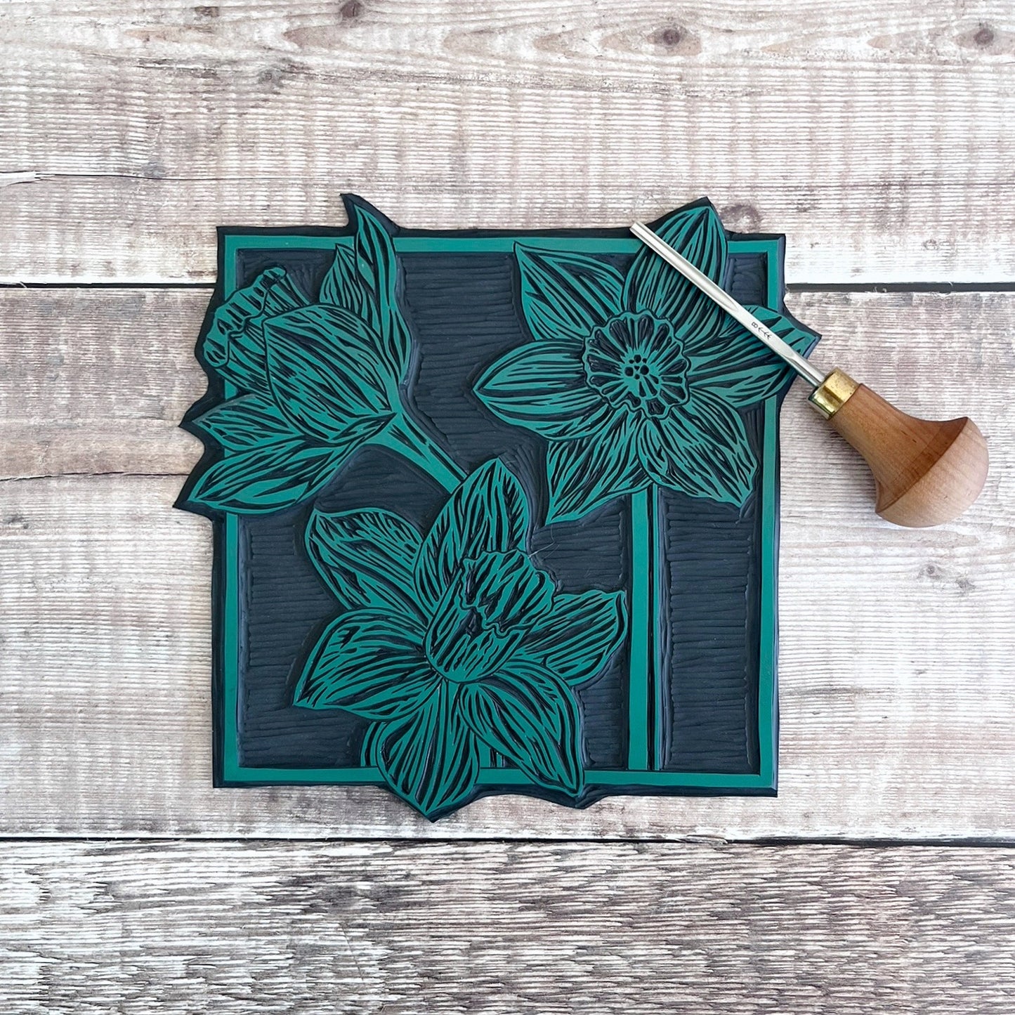 lino and cutting tool used for the Daffodils print, laid on a wooden surface

