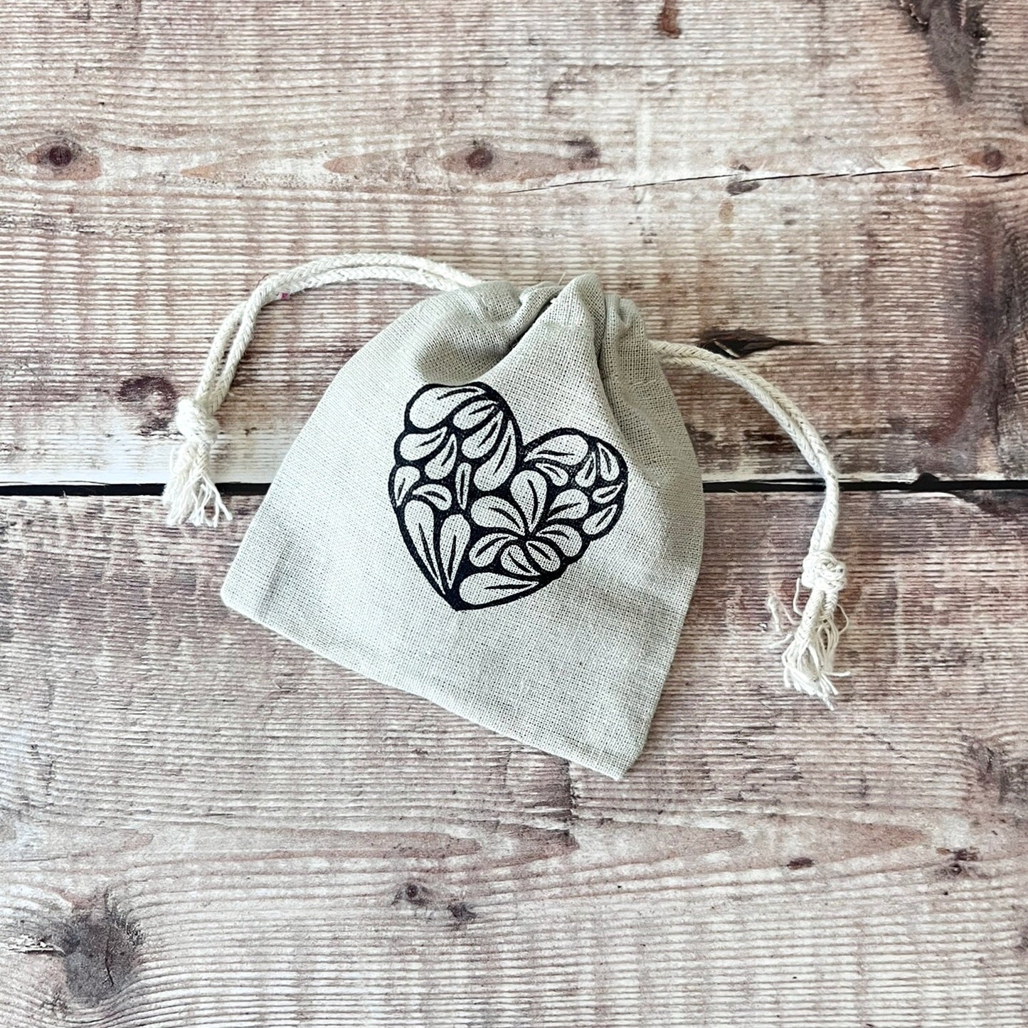 Small drawstring bag with a heart design on a wooden surface