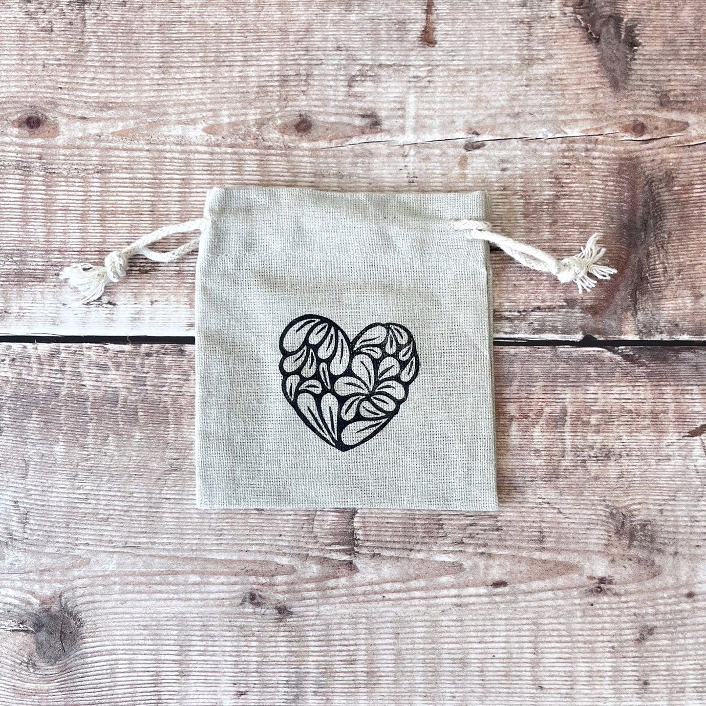 Small fabric pouch with a heart design on a wooden surface