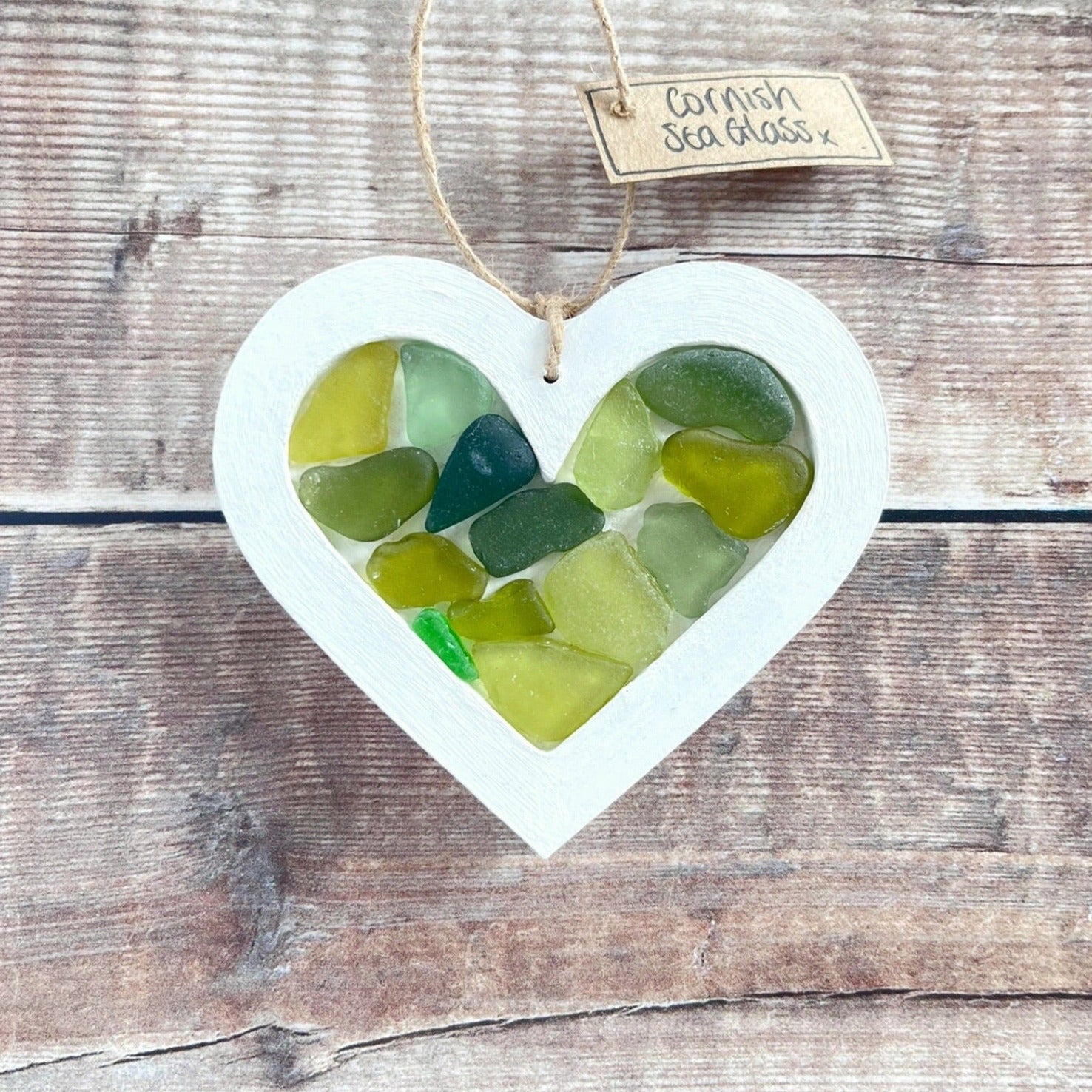 Heart-shaped sea glass hanging decoration with a 'Cornish Sea Glass' tag on a wooden surface