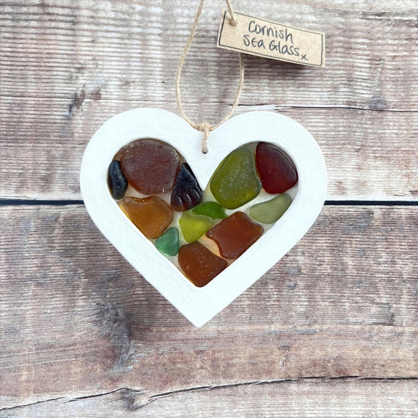 Heart-shaped sea glass hanging decoration with a 'Cornish Sea Glass' tag on a wooden surface
