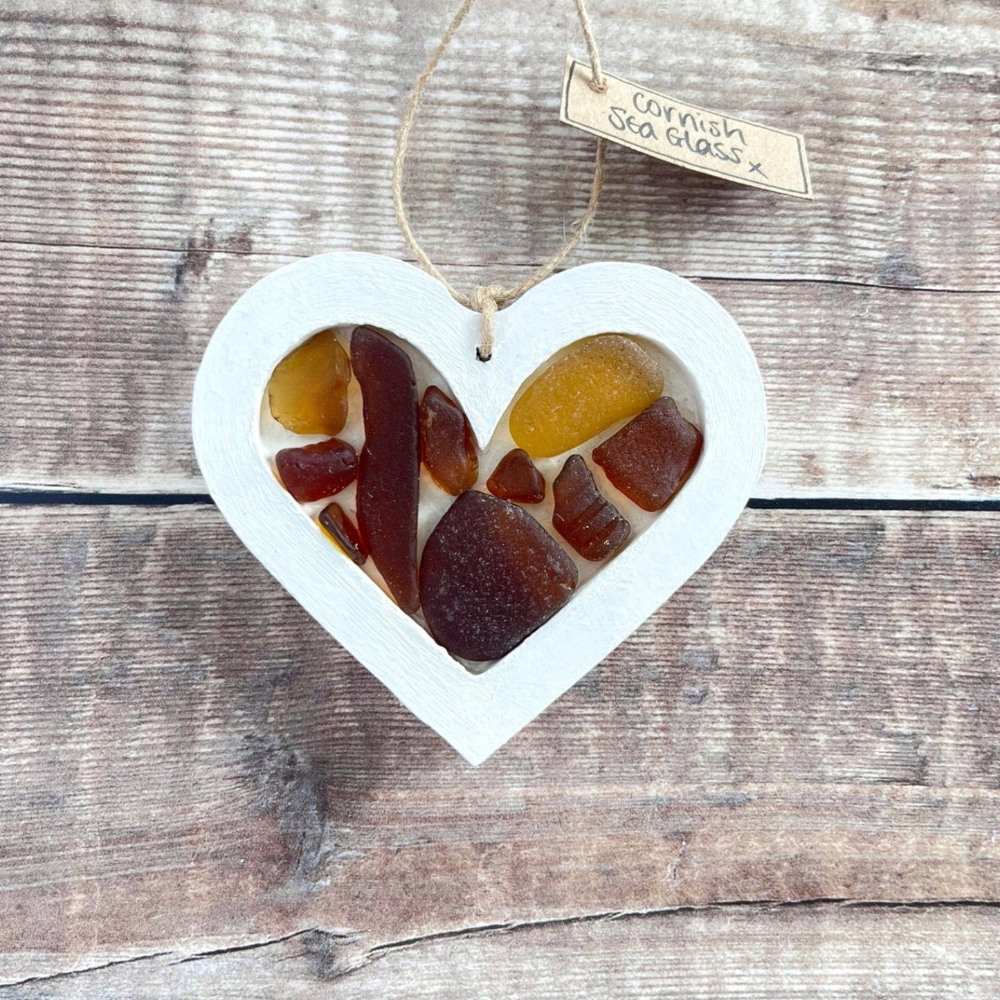 Heart-shaped sea glass hanging decoration with a 'Cornish Sea Glass' tag on a wooden surface