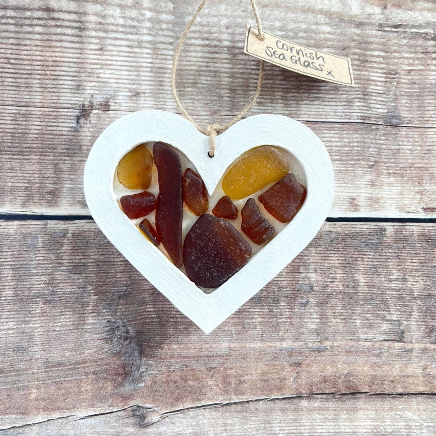 Heart-shaped sea glass hanging decoration with a 'Cornish Sea Glass' tag on a wooden surface