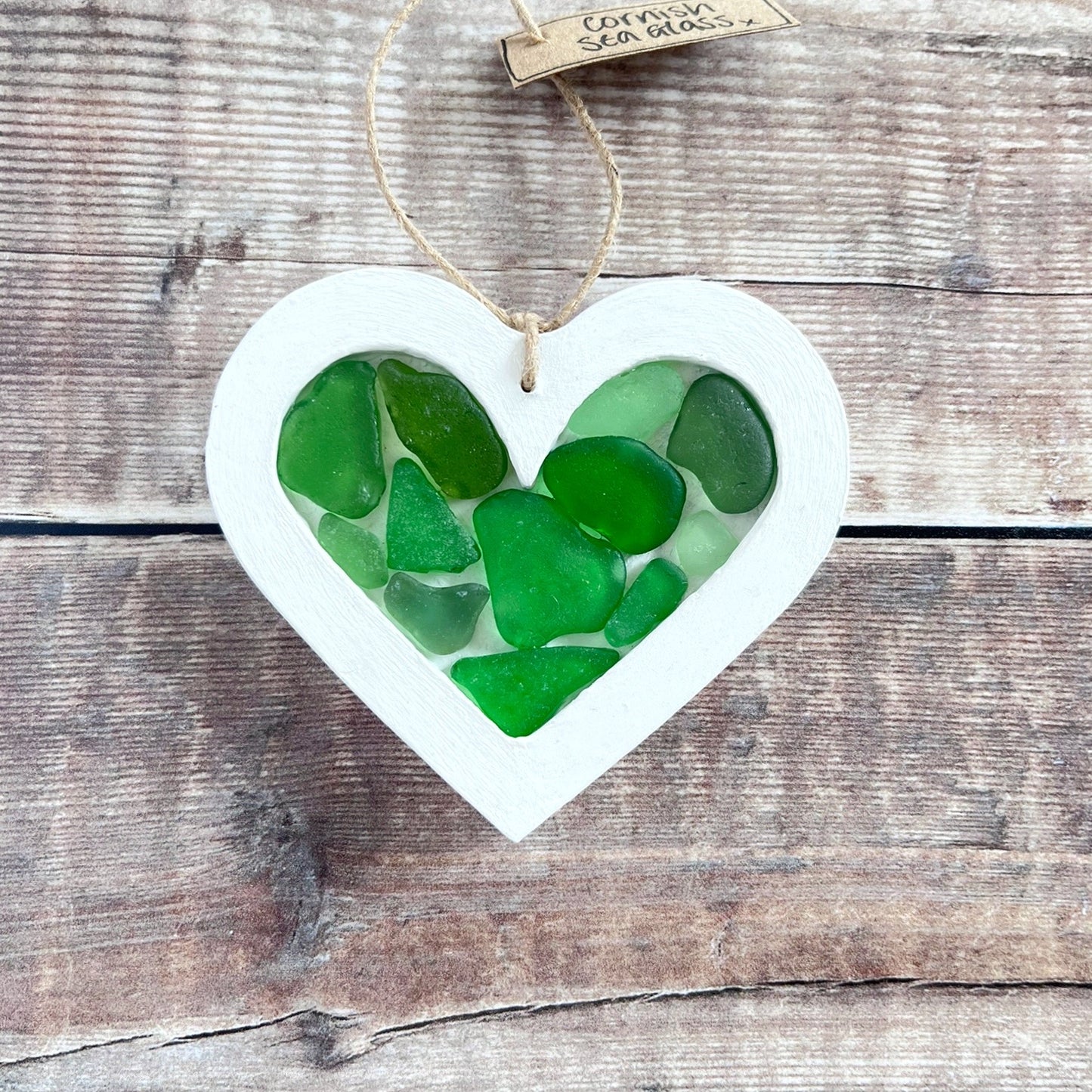 Heart-shaped sea glass hanging decoration with a 'Cornish Sea Glass' tag on a wooden surface