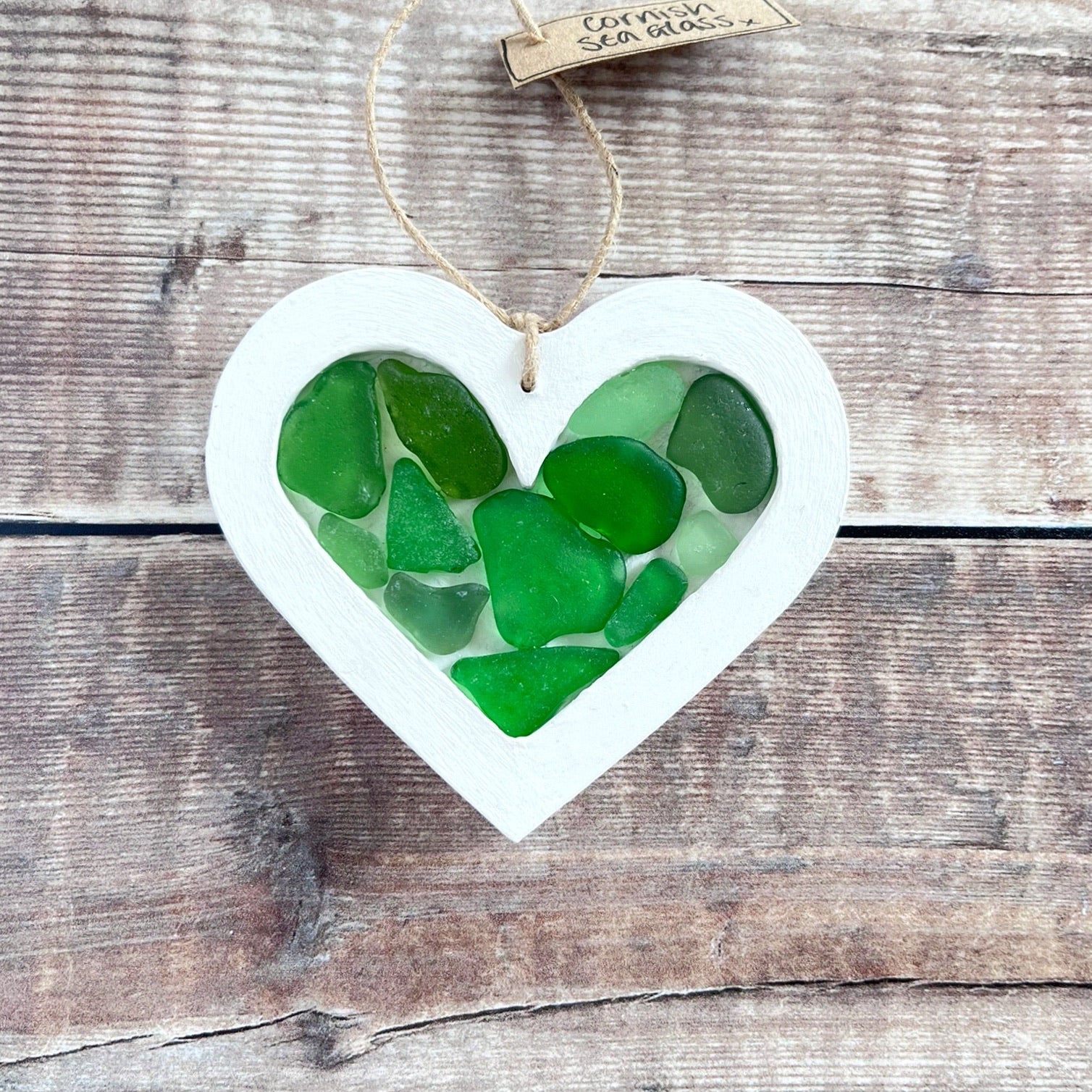 Heart-shaped sea glass hanging decoration with a 'Cornish Sea Glass' tag on a wooden surface