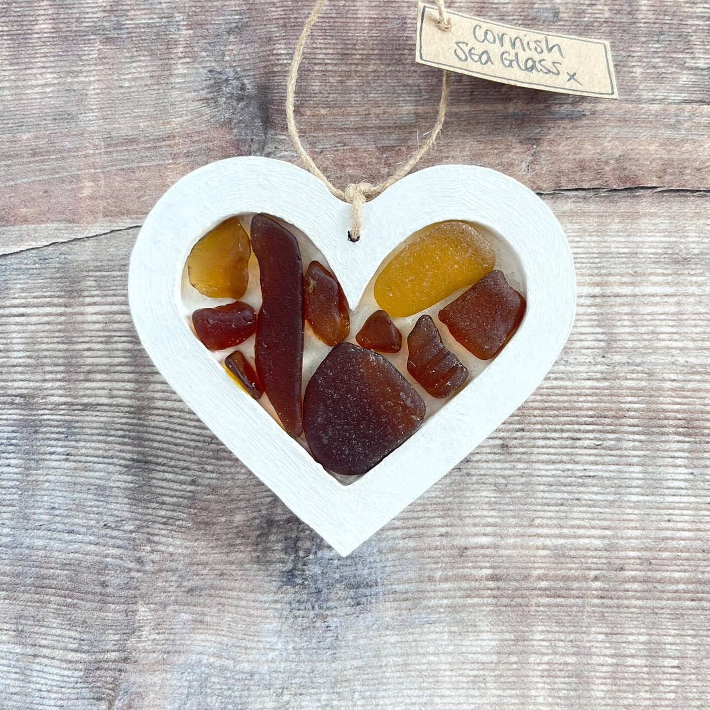 Heart-shaped sea glass hanging decoration with a 'Cornish Sea Glass' tag on a wooden surface