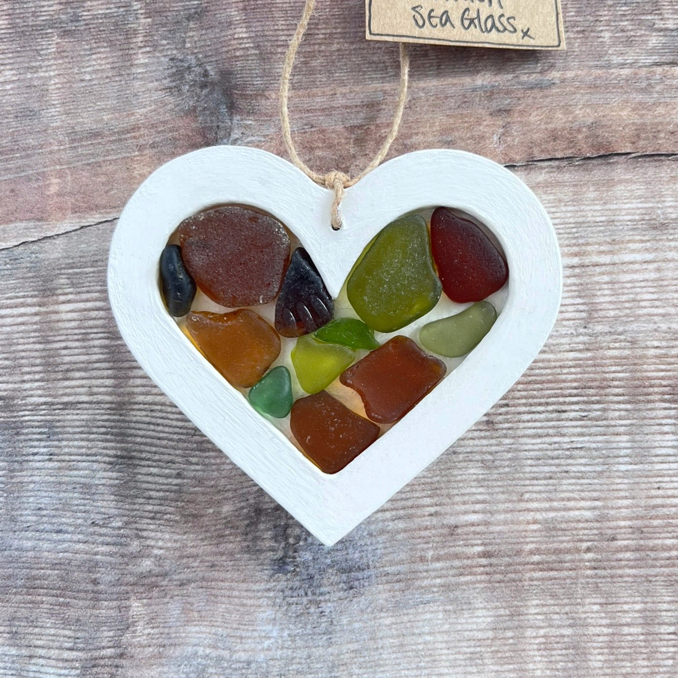 Heart-shaped sea glass hanging decoration with a 'Cornish Sea Glass' tag on a wooden surface