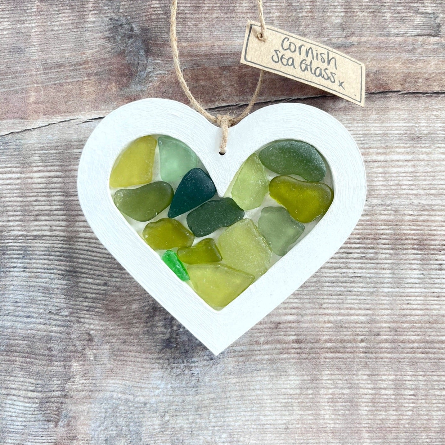 Heart-shaped sea glass hanging decoration with a 'Cornish Sea Glass' tag on a wooden surface
