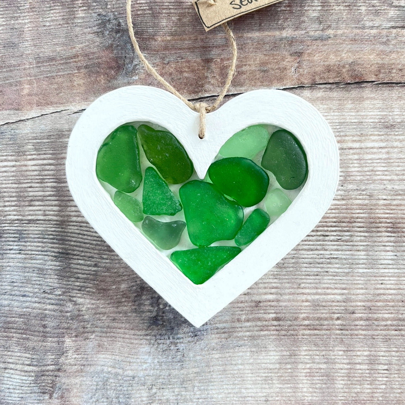 Heart-shaped sea glass hanging decoration with a 'Cornish Sea Glass' tag on a wooden surface