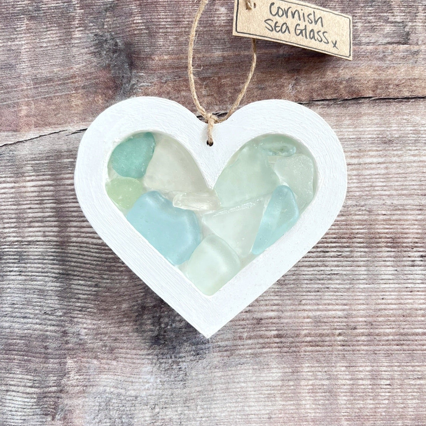 Heart-shaped sea glass hanging decoration with a 'Cornish Sea Glass' tag on a wooden surface